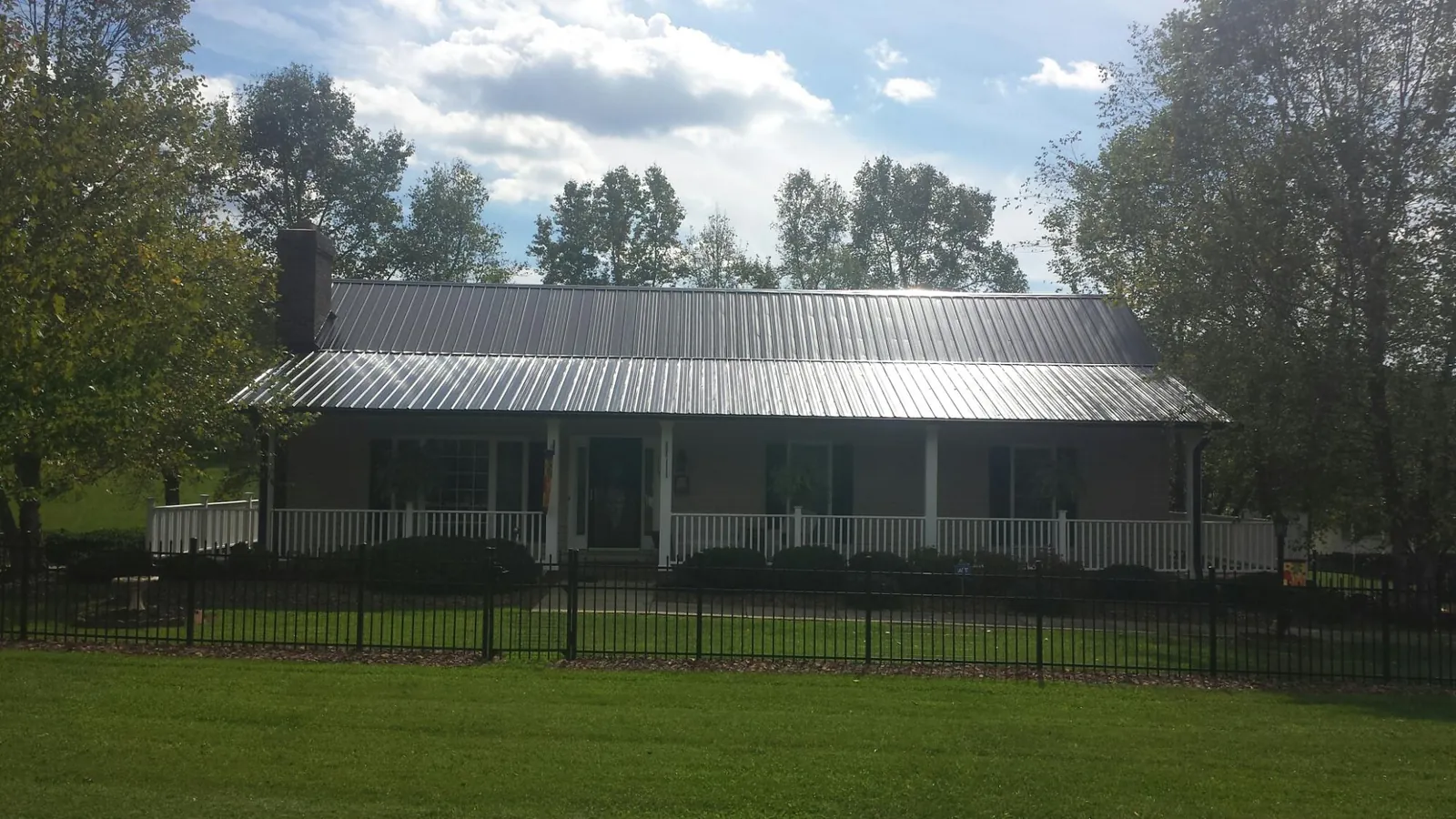 Gray metal roof on a brick ranch with a full width front porch — Gutter Guard Installation work by our crew in Lorida